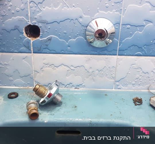חלקי ברז מפורקים על כיור בחדר אמבטיה